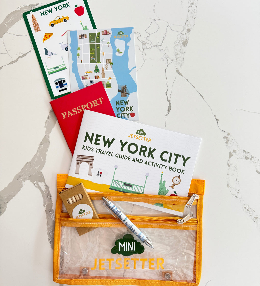  Travel-themed items including a passport, New York City guidebook, and pen on a marble surface.